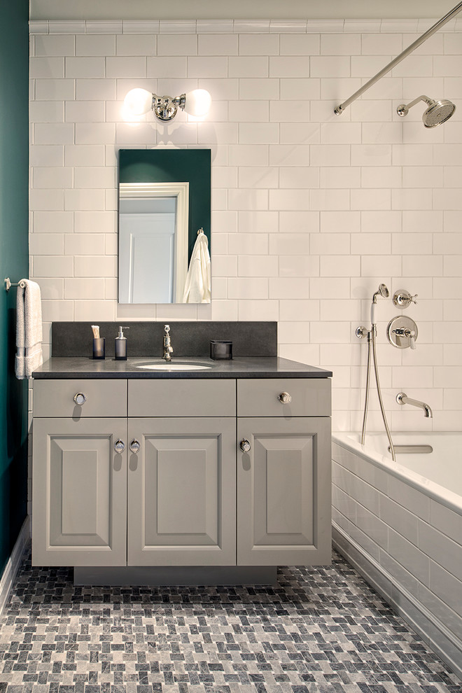 Medium sized mediterranean bathroom in San Francisco with raised-panel cabinets, grey cabinets, a built-in bath, a shower/bath combination, a two-piece toilet, white tiles, metro tiles, white walls, mosaic tile flooring, a submerged sink, limestone worktops, grey floors, a shower curtain and grey worktops.
