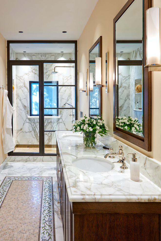 Inredning av ett medelhavsstil stort vit vitt en-suite badrum, med skåp i mellenmörkt trä, en dusch i en alkov, vit kakel, marmorkakel, beige väggar, marmorgolv, ett undermonterad handfat, marmorbänkskiva, vitt golv, dusch med gångjärnsdörr och luckor med upphöjd panel