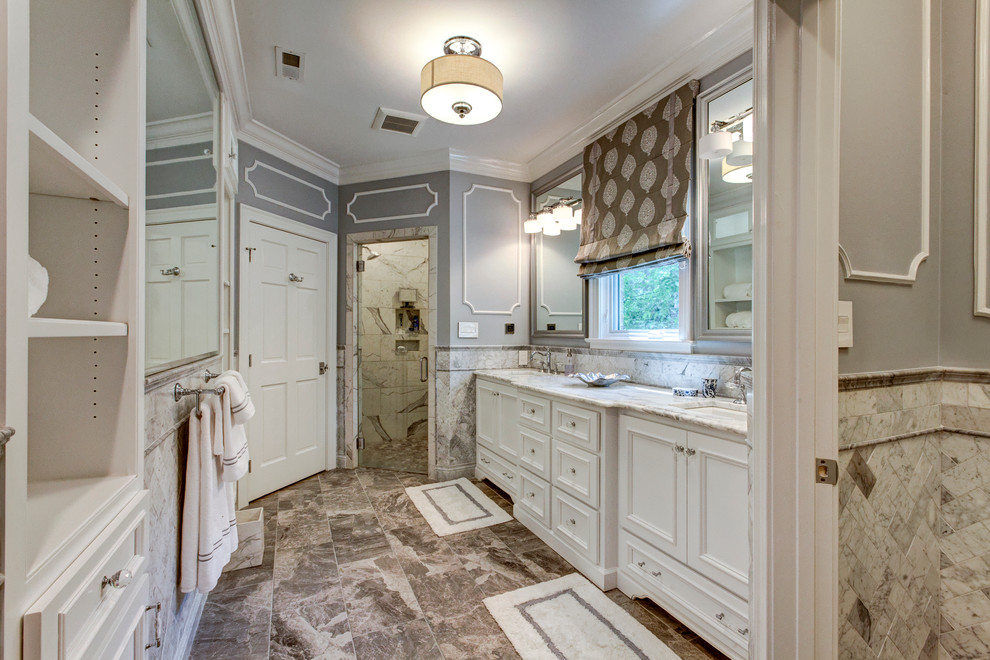 Пример оригинального дизайна: большая главная ванная комната в стиле неоклассика (современная классика) с белыми фасадами, угловым душем, унитазом-моноблоком, серой плиткой, каменной плиткой, серыми стенами, мраморным полом, врезной раковиной, мраморной столешницей и фасадами островного типа