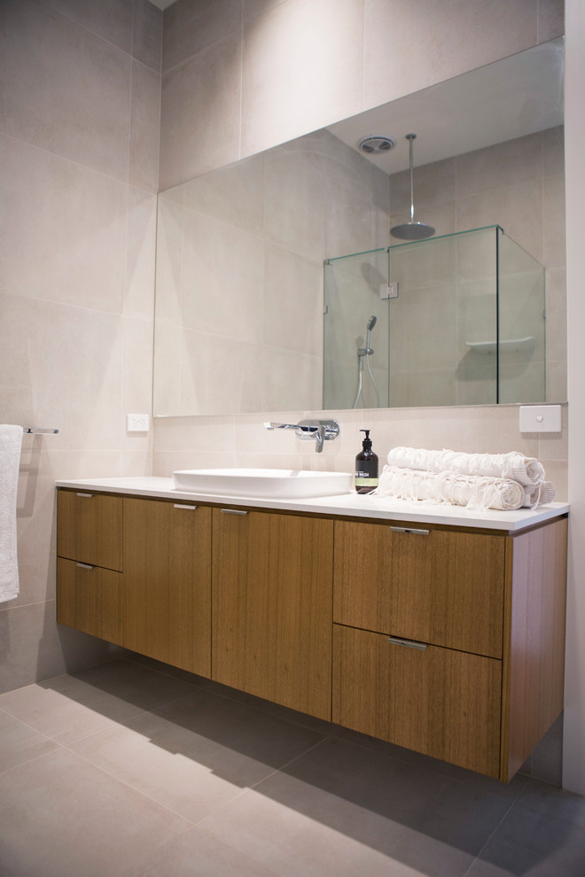 Inspiration for a medium sized contemporary bathroom in Melbourne with freestanding cabinets, medium wood cabinets, porcelain flooring, engineered stone worktops, a corner shower, grey tiles, stone slabs, grey walls and an integrated sink.