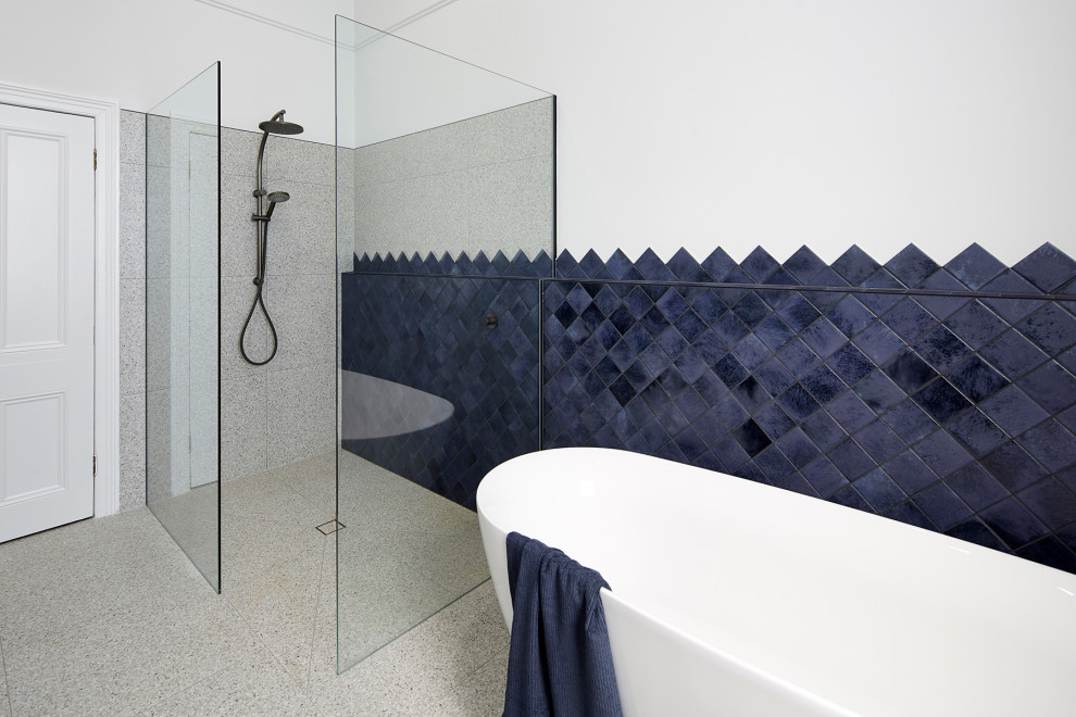 Inspiration for a large modern kids' gray tile terrazzo floor and multicolored floor bathroom remodel in Melbourne with flat-panel cabinets, blue cabinets, a wall-mount toilet, multicolored walls, a vessel sink, quartz countertops and white countertops