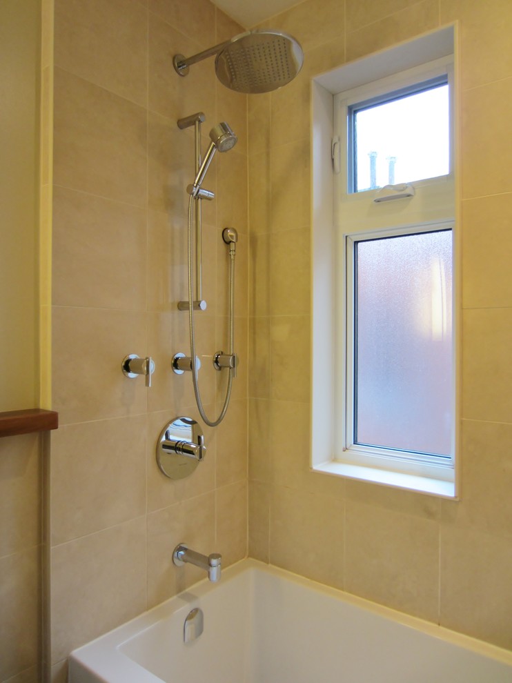 Idéer för att renovera ett litet funkis en-suite badrum, med ett fristående handfat, släta luckor, vita skåp, ett badkar i en alkov, en dusch/badkar-kombination, en toalettstol med hel cisternkåpa, beige kakel, stenkakel, beige väggar och mörkt trägolv