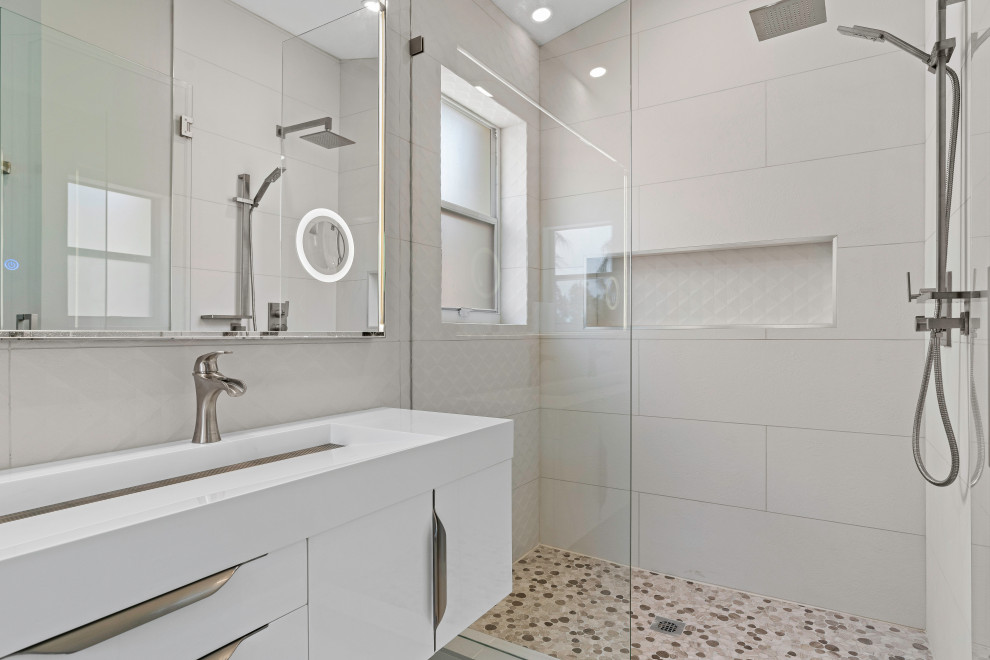 На фото: главная ванная комната среднего размера в стиле модернизм с плоскими фасадами, белыми фасадами, открытым душем, унитазом-моноблоком, бежевой плиткой, керамогранитной плиткой, серыми стенами, полом из керамогранита, раковиной с несколькими смесителями, столешницей из кварцита, серым полом, душем с распашными дверями, белой столешницей, нишей, тумбой под одну раковину и подвесной тумбой