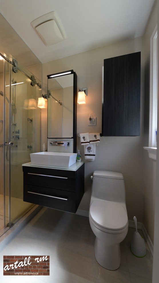 Design ideas for a small contemporary ensuite bathroom in Toronto with flat-panel cabinets, dark wood cabinets, an alcove shower, a one-piece toilet, grey tiles, porcelain tiles, beige walls, porcelain flooring, a vessel sink and glass worktops.