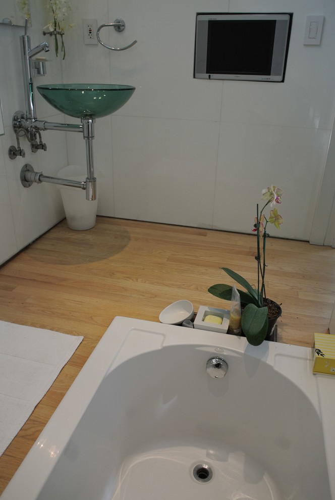 Inredning av ett modernt mellanstort badrum med dusch, med ett undermonterad handfat, bänkskiva i glas, ett platsbyggt badkar, en dusch/badkar-kombination, en toalettstol med hel cisternkåpa, vit kakel, glaskakel, vita väggar och ljust trägolv