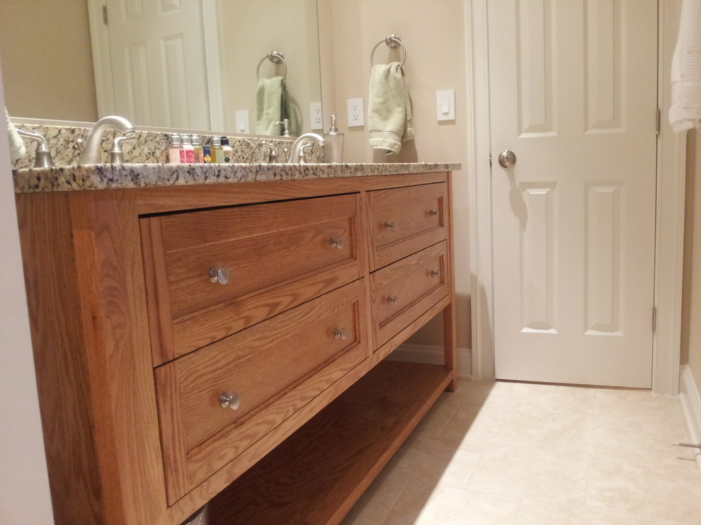 Exemple d'une salle de bain chic en bois clair avec un placard à porte shaker et un plan de toilette en granite.