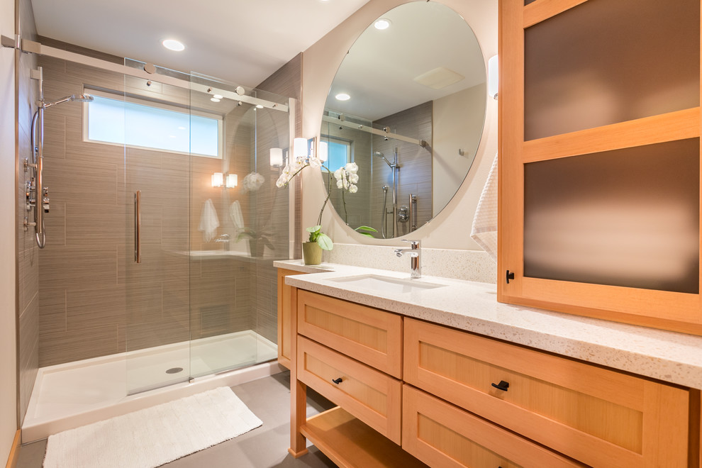 Exempel på ett mellanstort modernt badrum med dusch, med skåp i ljust trä, en öppen dusch, en toalettstol med separat cisternkåpa, grå kakel, keramikplattor, beige väggar, laminatgolv, ett undermonterad handfat, grått golv, dusch med skjutdörr, luckor med infälld panel och bänkskiva i akrylsten