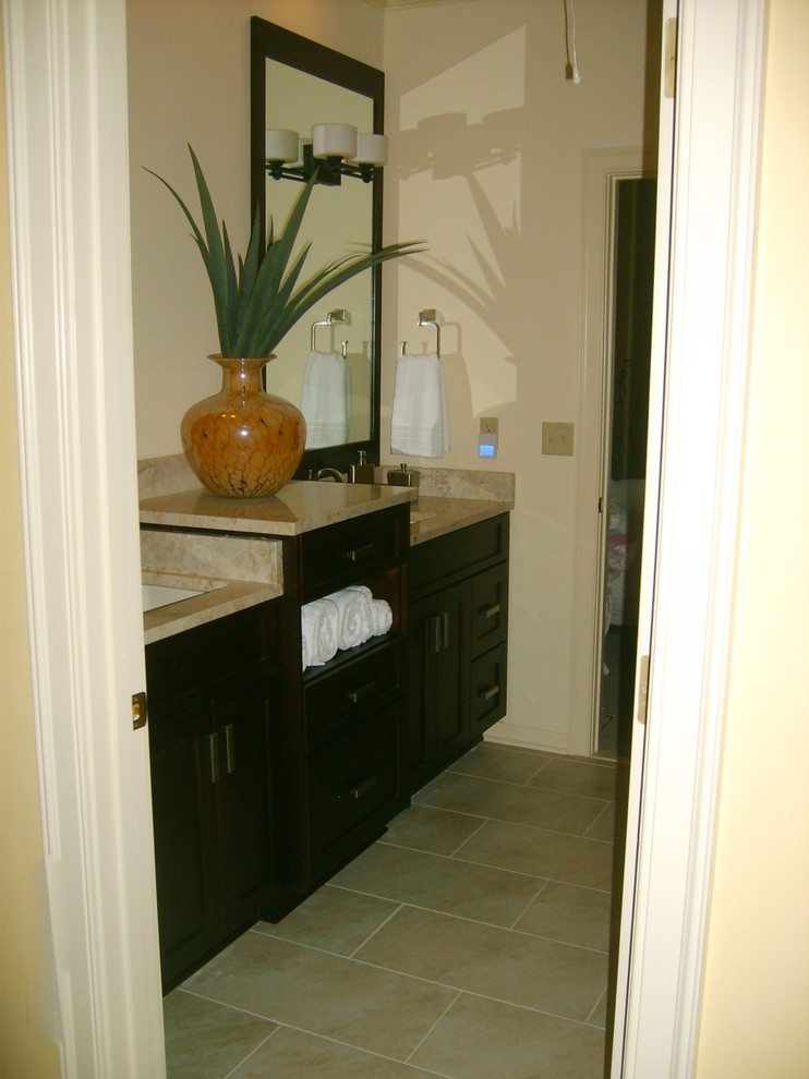 Bild på ett vintage badrum, med ett undermonterad handfat, luckor med infälld panel, skåp i mörkt trä, marmorbänkskiva, en toalettstol med separat cisternkåpa, beige kakel och porslinskakel
