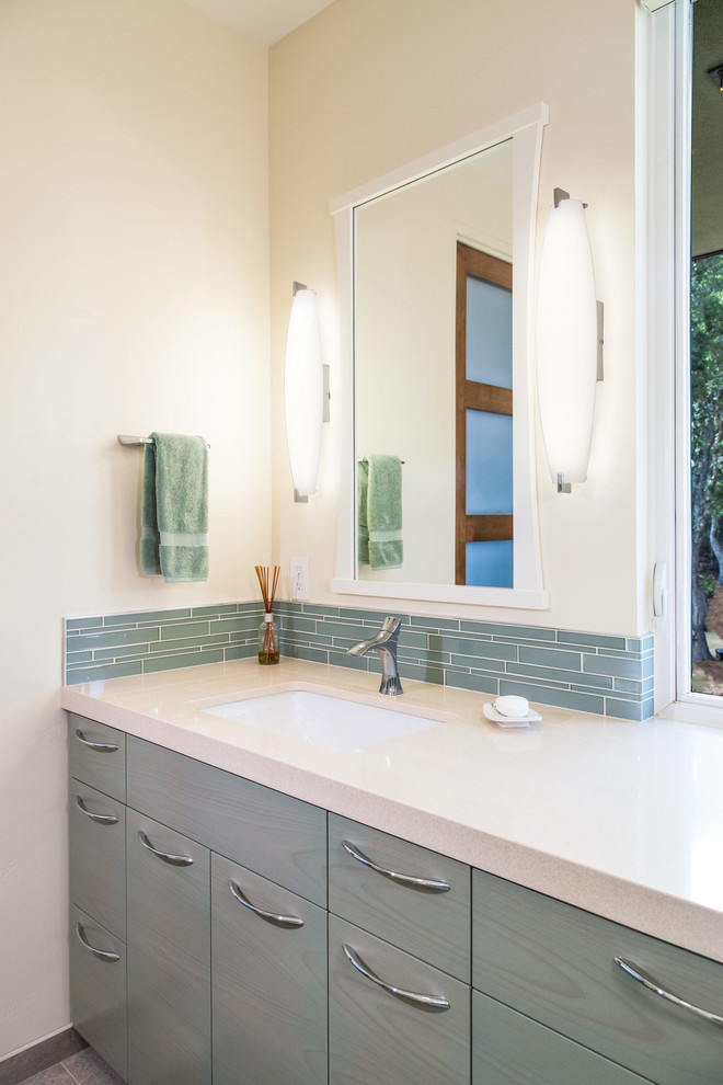 Example of a small minimalist kids' beige tile and glass sheet porcelain tile bathroom design in San Francisco with flat-panel cabinets, turquoise cabinets, a wall-mount toilet, beige walls and an undermount sink