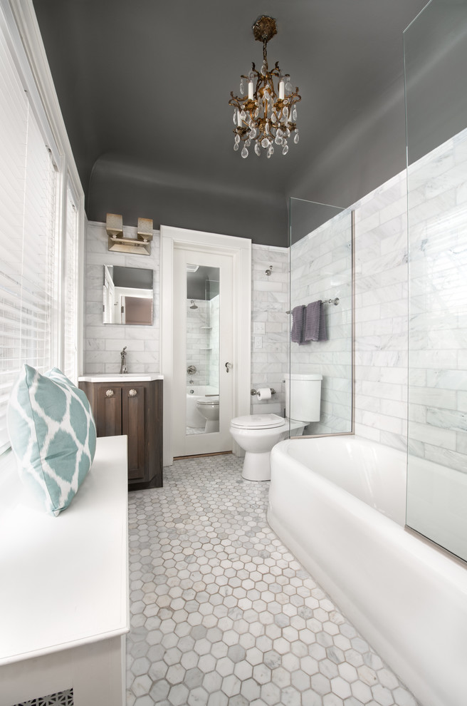 Klassisk inredning av ett litet vit vitt badrum, med möbel-liknande, bruna skåp, ett hörnbadkar, en dusch/badkar-kombination, en toalettstol med separat cisternkåpa, vit kakel, tunnelbanekakel, grå väggar, marmorgolv, ett undermonterad handfat, bänkskiva i kvarts, vitt golv och med dusch som är öppen