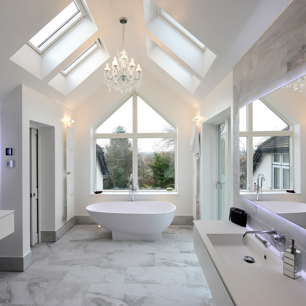 Пример оригинального дизайна: большая ванная комната в современном стиле с плоскими фасадами, белыми фасадами, отдельно стоящей ванной, душем над ванной, серой плиткой, мраморным полом и подвесной раковиной
