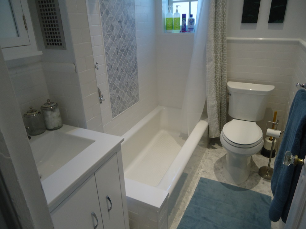 ニューヨークにある中くらいなトランジショナルスタイルのおしゃれなマスターバスルーム (一体型シンク、シェーカースタイル扉のキャビネット、白いキャビネット、クオーツストーンの洗面台、アルコーブ型浴槽、シャワー付き浴槽	、分離型トイレ、白いタイル、セラミックタイル、白い壁、磁器タイルの床) の写真
