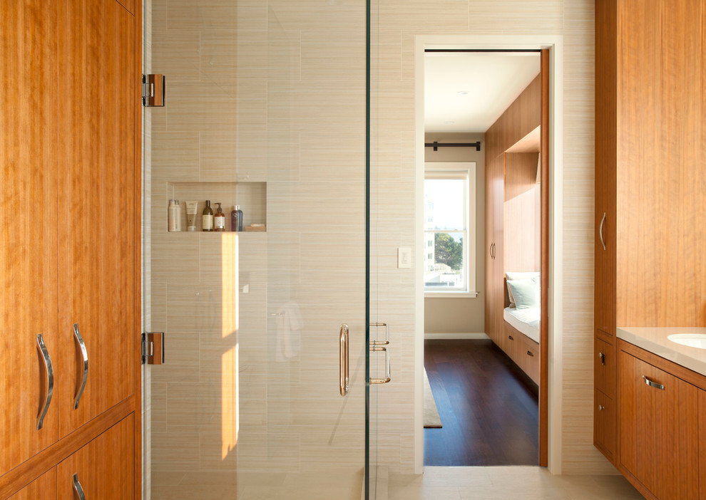 Réalisation d'une grande salle de bain principale design en bois clair avec un placard à porte plane, une baignoire indépendante et un lavabo encastré.