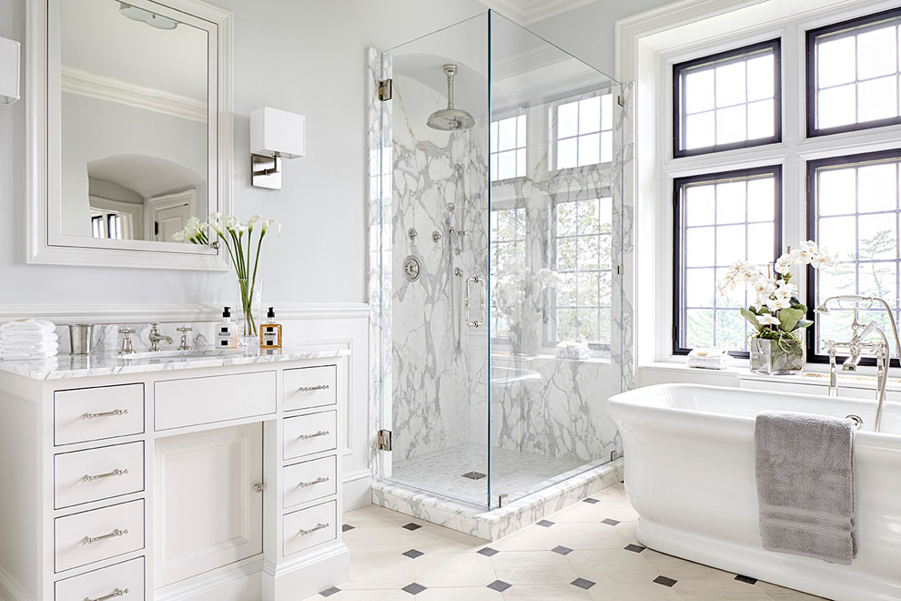 ニューヨークにあるトラディショナルスタイルのおしゃれなマスターバスルーム (白いキャビネット、置き型浴槽、コーナー設置型シャワー、白いタイル、石スラブタイル、グレーの壁、アンダーカウンター洗面器、マルチカラーの床、開き戸のシャワー) の写真