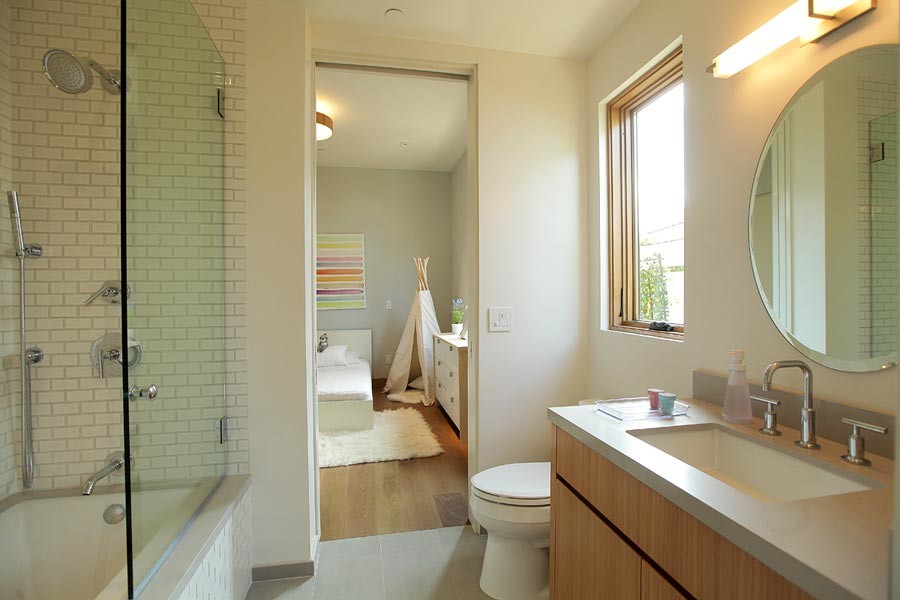 Photo of a medium sized retro family bathroom in Los Angeles with a submerged sink, flat-panel cabinets, medium wood cabinets, engineered stone worktops, a built-in bath, a shower/bath combination, a one-piece toilet, white tiles, porcelain tiles, white walls and medium hardwood flooring.