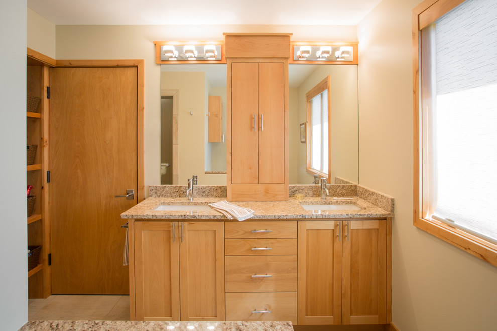 Cette image montre une salle de bain principale craftsman en bois clair de taille moyenne avec un placard à porte plane, un plan de toilette en granite, un carrelage beige, des carreaux de céramique, un lavabo encastré, un mur beige et un sol en carrelage de céramique.