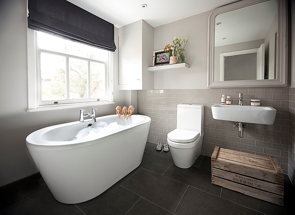 Photo of a medium sized contemporary family bathroom in Surrey with a wall-mounted sink, a freestanding bath, a one-piece toilet and ceramic flooring.