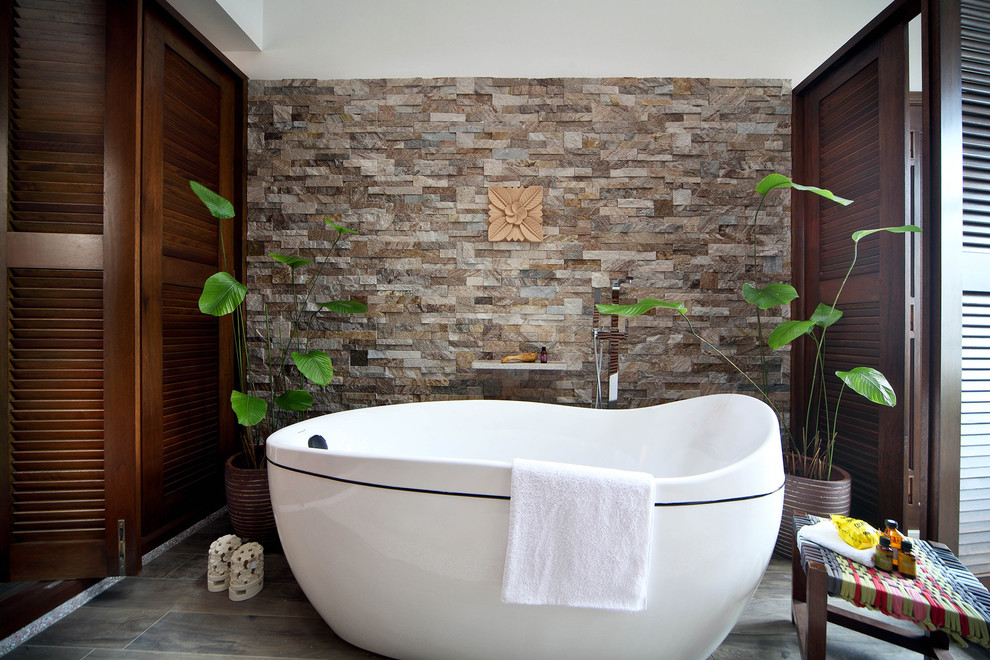 Inspiration pour une petite salle de bain asiatique avec une baignoire indépendante et un mur en pierre.