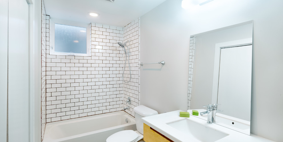 Example of a mid-sized minimalist white tile concrete floor alcove bathtub design in Columbus with a two-piece toilet, white walls, an undermount sink and quartzite countertops