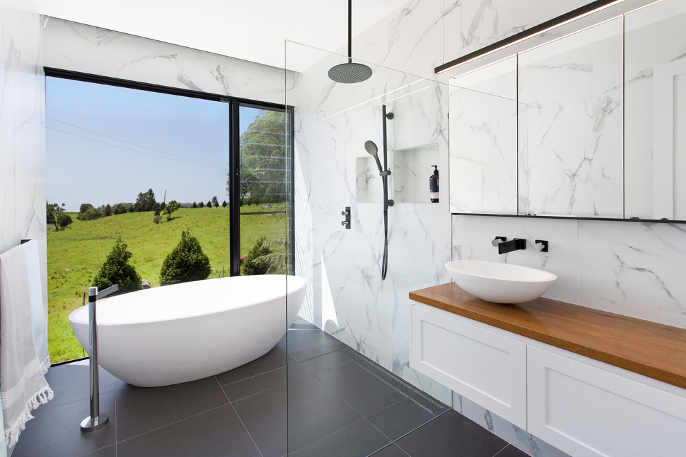 Esempio di una stanza da bagno per bambini design con vasca freestanding, piastrelle di marmo e pavimento grigio