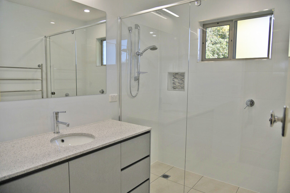Inredning av ett modernt litet grå grått en-suite badrum, med släta luckor, grå skåp, en kantlös dusch, vit kakel, keramikplattor, vita väggar, klinkergolv i keramik, ett undermonterad handfat, bänkskiva i kvarts, grått golv och dusch med gångjärnsdörr