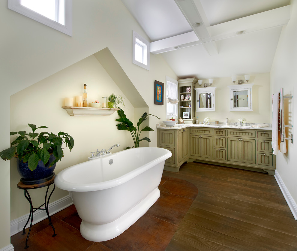 Foto på ett stort vintage en-suite badrum, med ett fristående badkar, mörkt trägolv, ett undermonterad handfat, marmorbänkskiva, gröna skåp, gula väggar, en kantlös dusch och luckor med infälld panel
