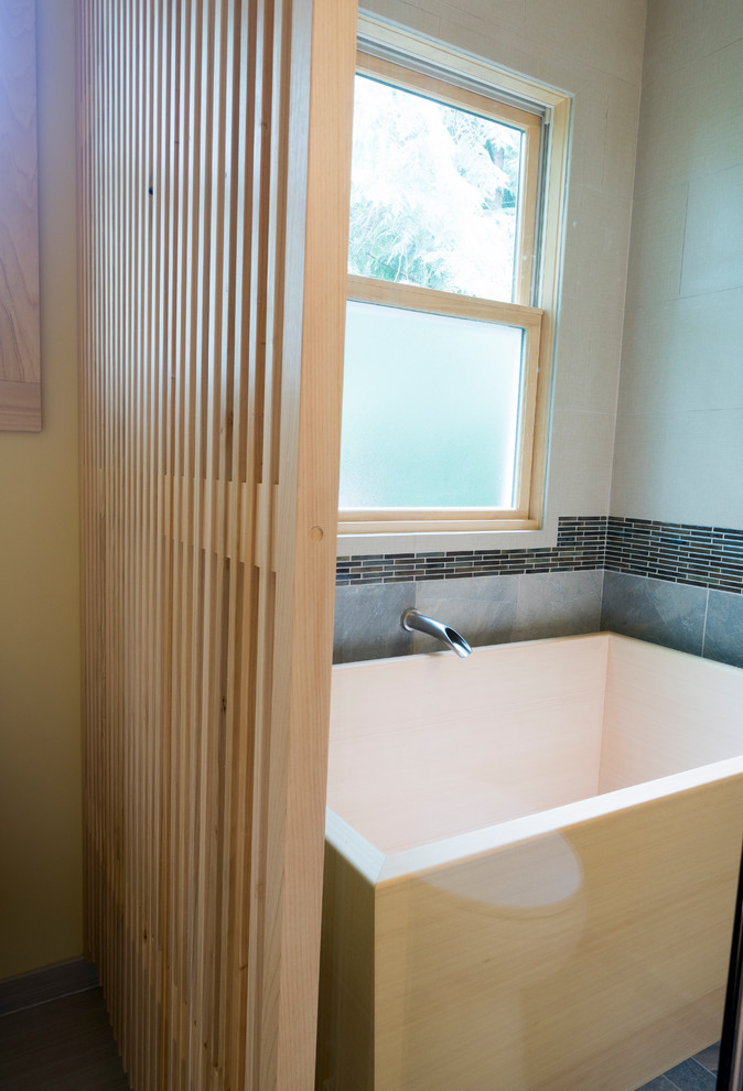 На фото: главная ванная комната среднего размера в восточном стиле с плоскими фасадами, светлыми деревянными фасадами, отдельно стоящей ванной, угловым душем, раздельным унитазом, серой плиткой, плиткой из сланца, белыми стенами, полом из керамогранита, врезной раковиной, столешницей из искусственного кварца, серым полом, душем с распашными дверями и белой столешницей