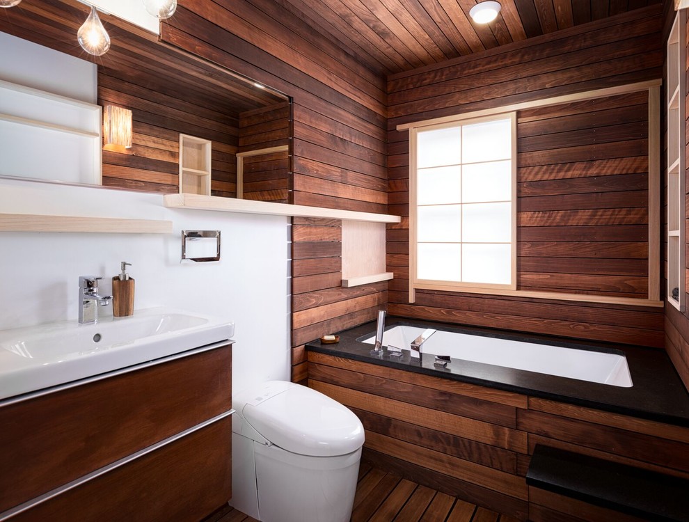 Idéer för mellanstora orientaliska badrum, med släta luckor, skåp i mörkt trä, ett undermonterat badkar, en vägghängd toalettstol, vita väggar, mörkt trägolv, ett integrerad handfat och brunt golv