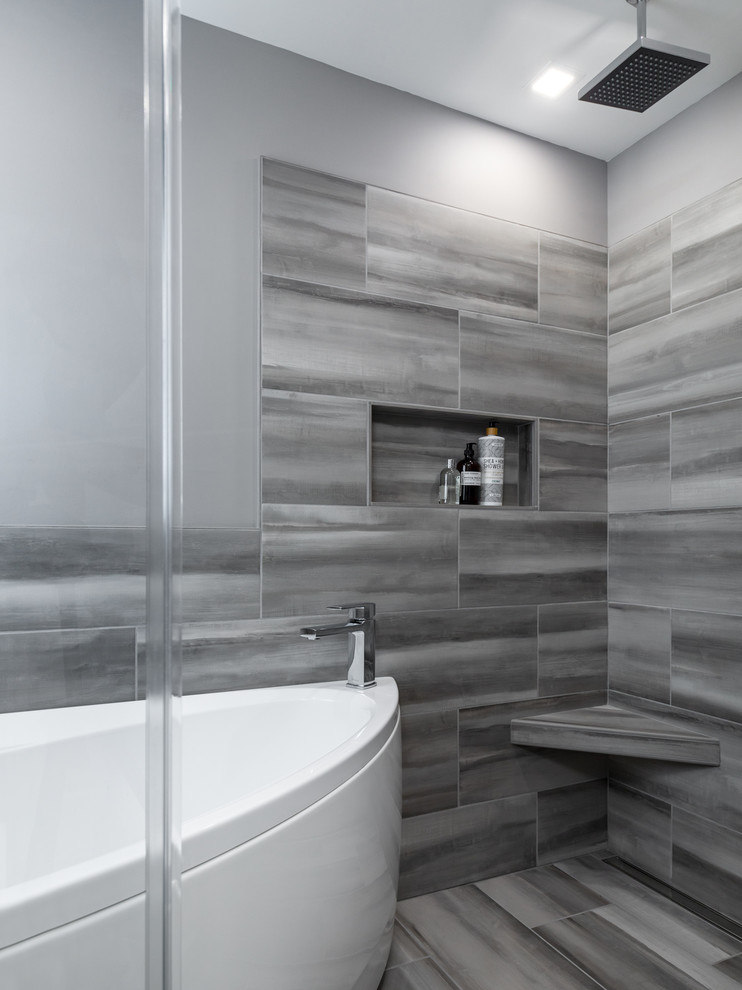 На фото: главная ванная комната среднего размера в стиле модернизм с угловой ванной, душем над ванной, серой плиткой, керамогранитной плиткой, серыми стенами, полом из керамогранита, серым полом и душем с распашными дверями