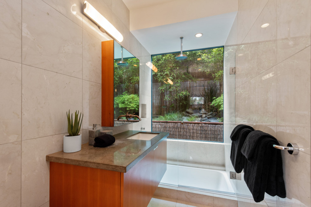 Стильный дизайн: главная ванная комната среднего размера в восточном стиле с плоскими фасадами, коричневыми фасадами, японской ванной, душем над ванной, инсталляцией, бежевой плиткой, плиткой из известняка, бежевыми стенами, полом из известняка, врезной раковиной, мраморной столешницей, бежевым полом, открытым душем, зеленой столешницей, тумбой под одну раковину и подвесной тумбой - последний тренд