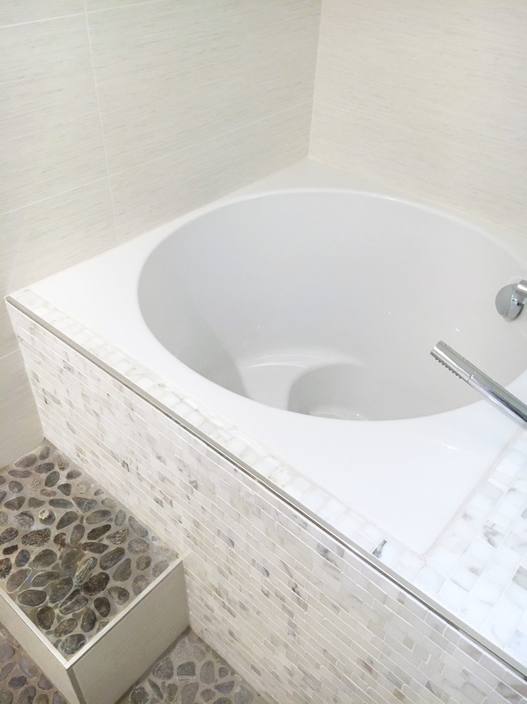 Réalisation d'une salle de bain tradition avec un bain japonais, WC à poser, des carreaux de porcelaine et un plan de toilette en quartz modifié.
