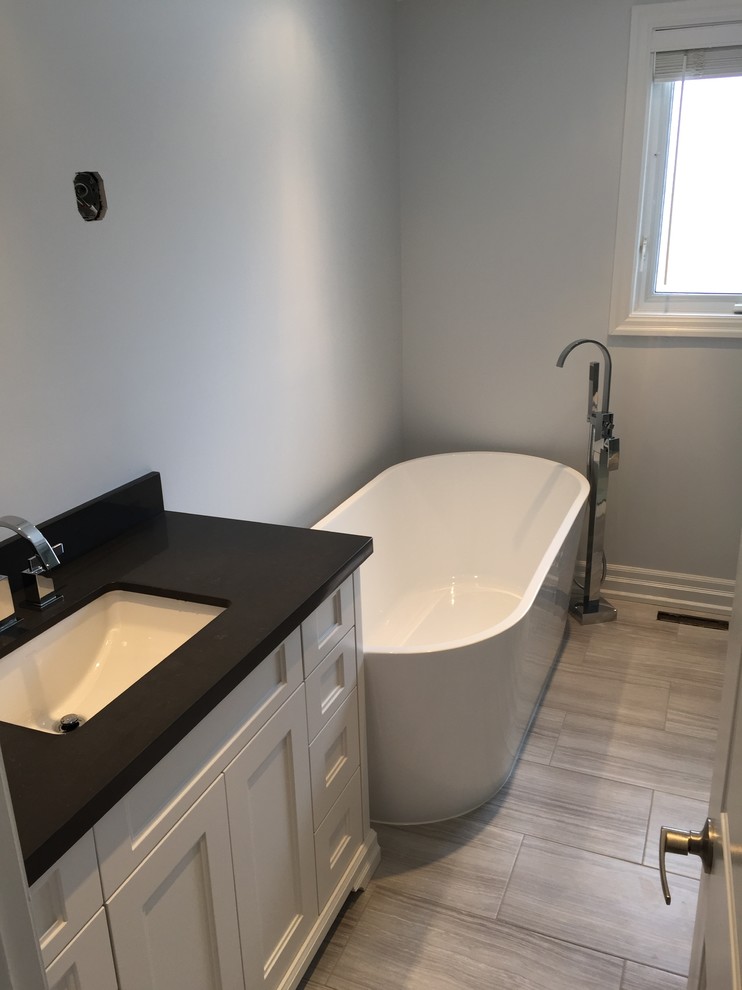 Inspiration för mellanstora moderna badrum med dusch, med skåp i shakerstil, vita skåp, ett fristående badkar, grå kakel, granitbänkskiva, dusch med gångjärnsdörr, en hörndusch, en toalettstol med separat cisternkåpa, grå väggar, klinkergolv i keramik, ett undermonterad handfat, grått golv och keramikplattor