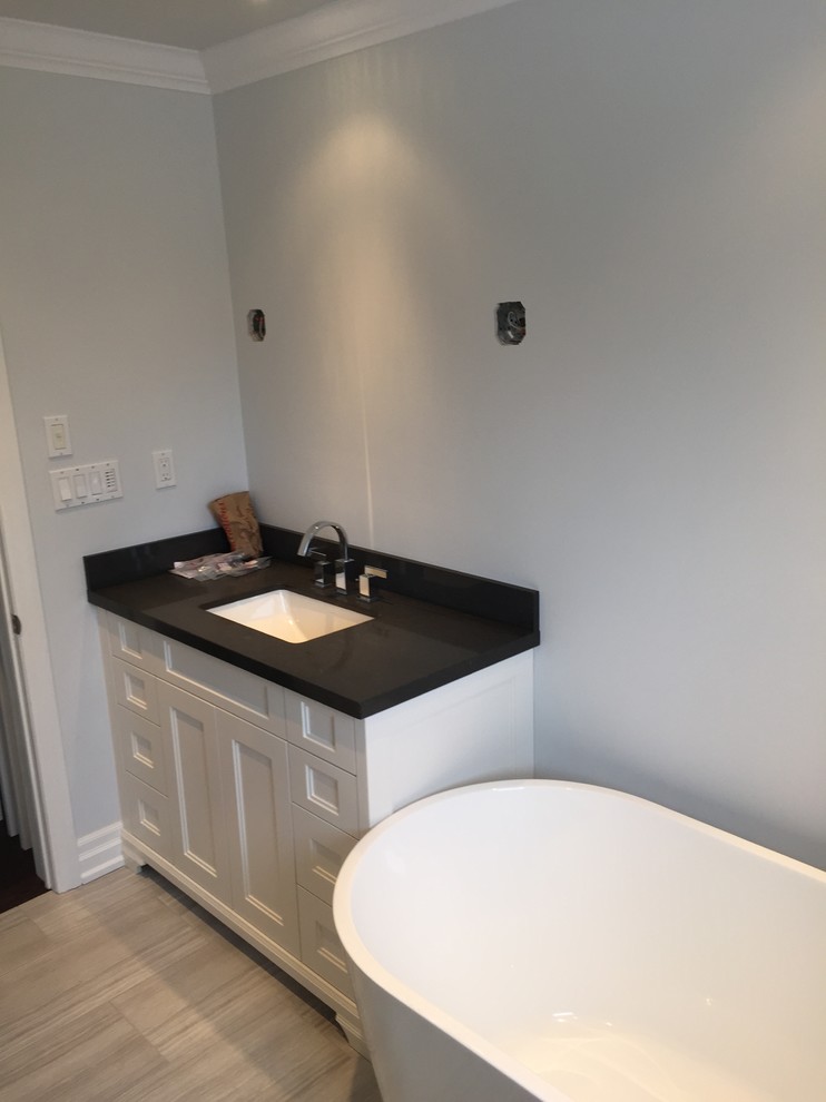 Exempel på ett mellanstort modernt badrum med dusch, med skåp i shakerstil, vita skåp, ett fristående badkar, en hörndusch, en toalettstol med separat cisternkåpa, grå kakel, keramikplattor, grå väggar, klinkergolv i keramik, ett undermonterad handfat, granitbänkskiva, grått golv och dusch med gångjärnsdörr