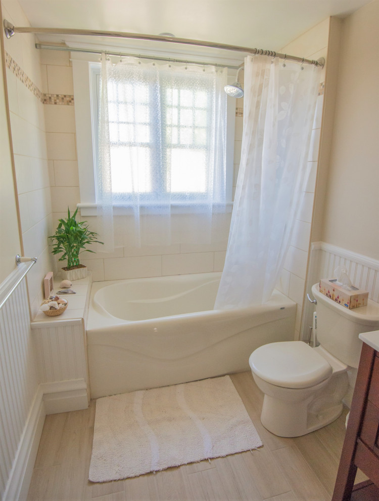 Inredning av ett klassiskt litet badrum, med skåp i mellenmörkt trä, ett badkar i en alkov, en dusch/badkar-kombination, en toalettstol med separat cisternkåpa, beige kakel, porslinskakel, beiget golv och dusch med duschdraperi