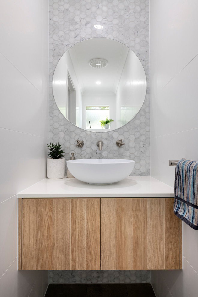 Foto de cuarto de baño contemporáneo con armarios con paneles lisos, puertas de armario de madera clara, baldosas y/o azulejos blancos, baldosas y/o azulejos en mosaico, paredes blancas, lavabo sobreencimera y encimeras blancas