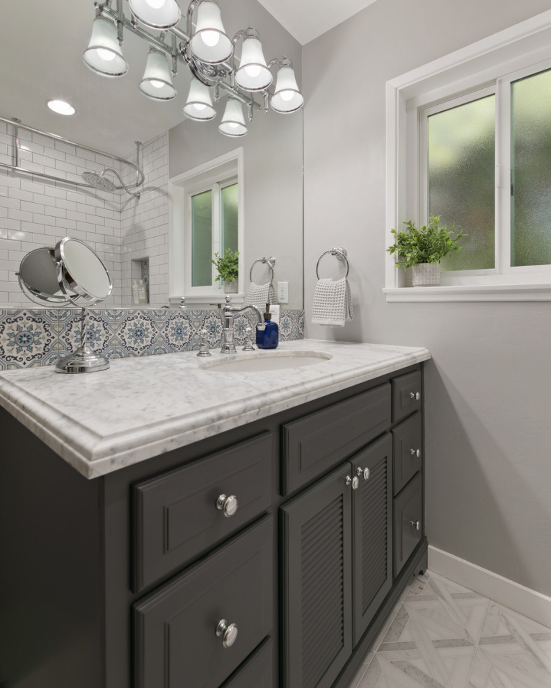 Inredning av ett nordiskt mellanstort vit vitt badrum, med luckor med upphöjd panel, grå skåp, en dusch/badkar-kombination, vit kakel, grå väggar, klinkergolv i porslin, ett nedsänkt handfat, marmorbänkskiva och vitt golv