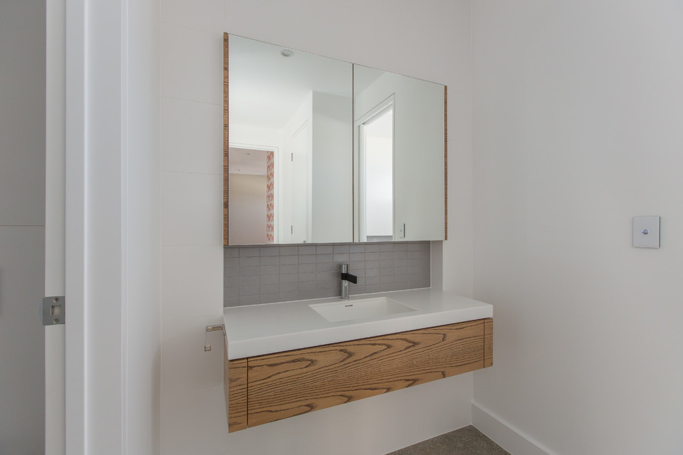 Idéer för ett litet modernt badrum med dusch, med släta luckor, skåp i mellenmörkt trä, en öppen dusch, en toalettstol med separat cisternkåpa, vita väggar, betonggolv, ett undermonterad handfat och bänkskiva i akrylsten