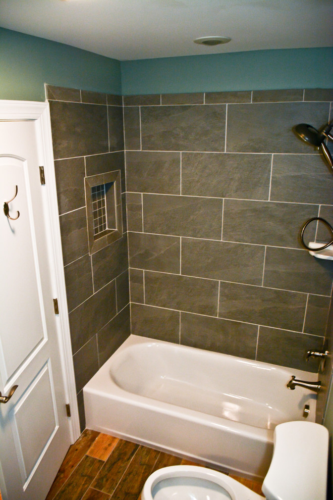 Idee per una piccola stanza da bagno design con vasca ad alcova, vasca/doccia, WC a due pezzi, piastrelle nere, piastrelle in ardesia, pareti blu, pavimento in legno massello medio, lavabo sottopiano, pavimento marrone e doccia aperta