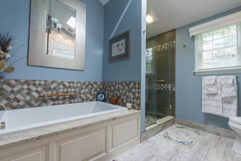 Medium sized traditional ensuite bathroom in Other with a built-in sink, freestanding cabinets, white cabinets, granite worktops, an alcove bath, an alcove shower, a two-piece toilet, multi-coloured tiles, glass sheet walls, blue walls and porcelain flooring.