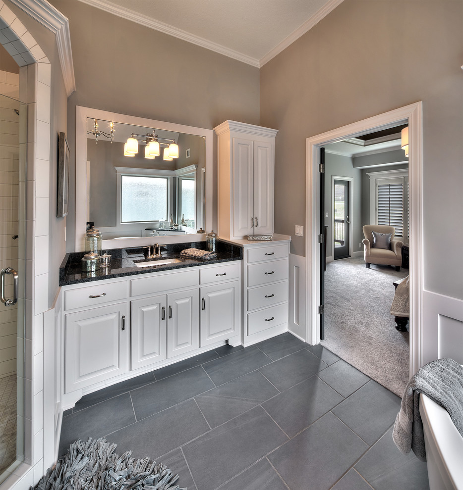 Design ideas for a large traditional ensuite bathroom in Kansas City with raised-panel cabinets, white cabinets, a freestanding bath, a corner shower, a two-piece toilet, grey tiles, ceramic tiles, grey walls, ceramic flooring, a submerged sink and granite worktops.