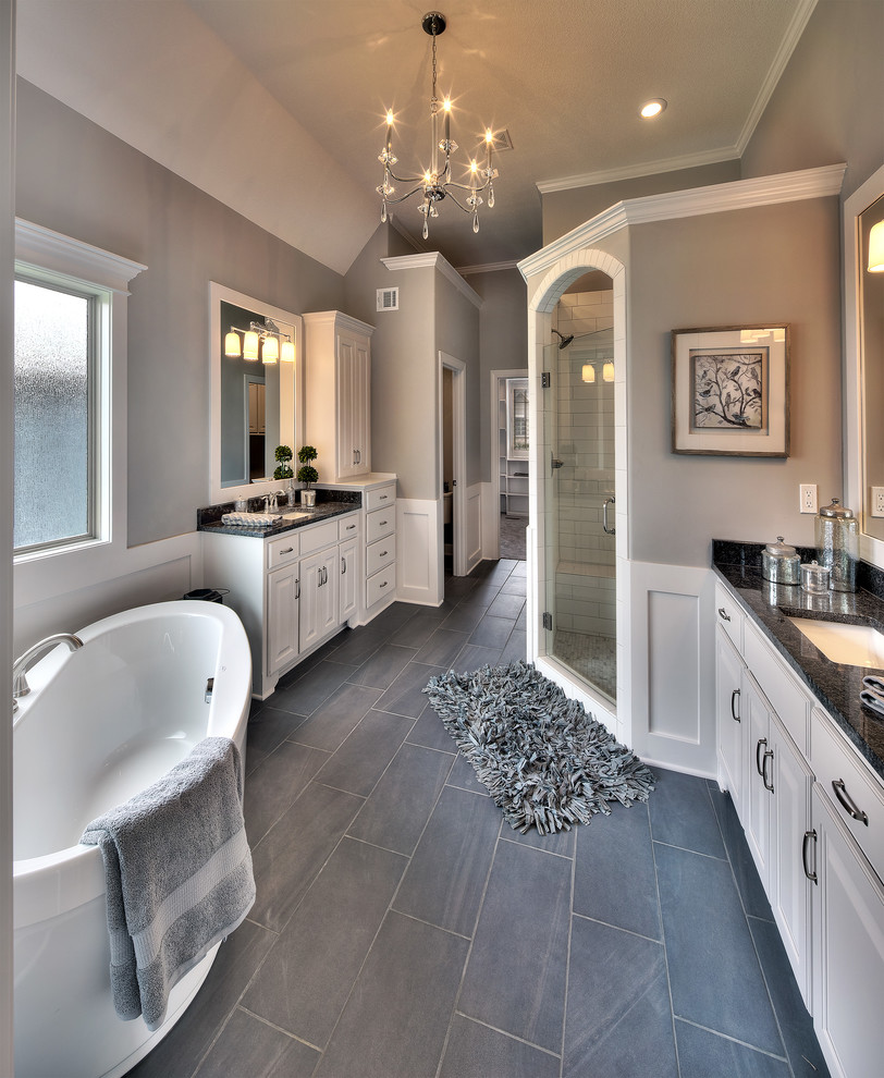 Стильный дизайн: большая главная ванная комната в классическом стиле с фасадами с выступающей филенкой, белыми фасадами, отдельно стоящей ванной, угловым душем, раздельным унитазом, серой плиткой, керамической плиткой, серыми стенами, полом из керамической плитки, врезной раковиной и столешницей из гранита - последний тренд