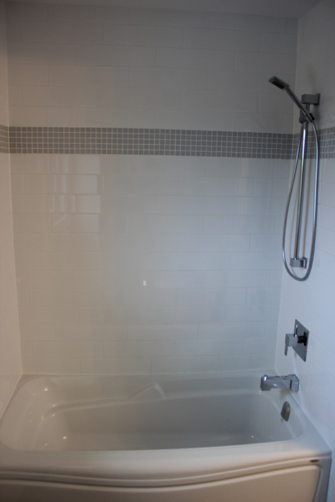 Foto di una stanza da bagno per bambini design con vasca da incasso, vasca/doccia, piastrelle grigie, piastrelle di vetro, pareti bianche e pavimento in gres porcellanato