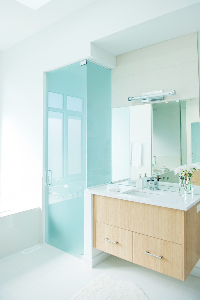 Esempio di una stanza da bagno moderna con ante lisce, ante in legno chiaro e doccia alcova