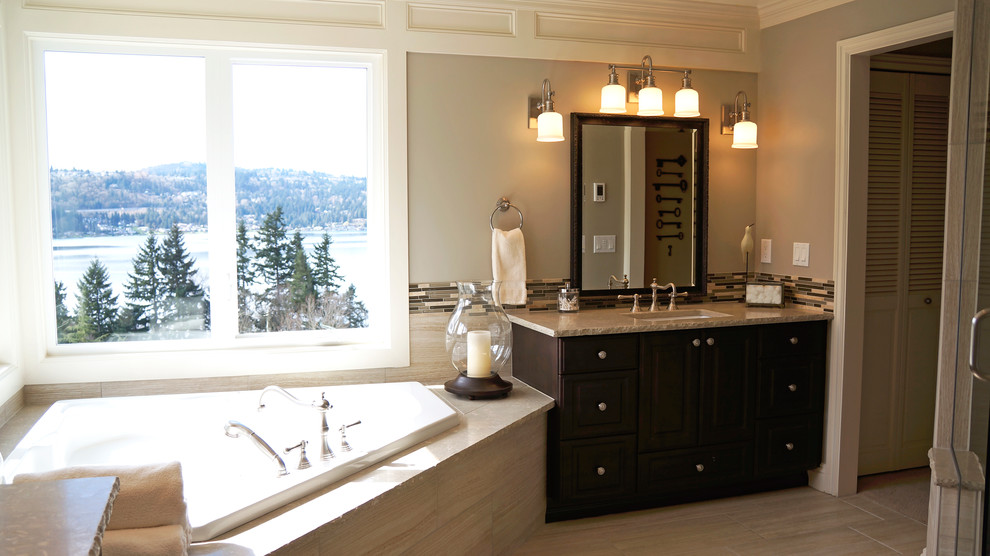 Inspiration for a large traditional ensuite bathroom in Seattle with a submerged sink, raised-panel cabinets, dark wood cabinets, limestone worktops, a corner bath, a double shower, a one-piece toilet, beige tiles, porcelain tiles, beige walls and porcelain flooring.