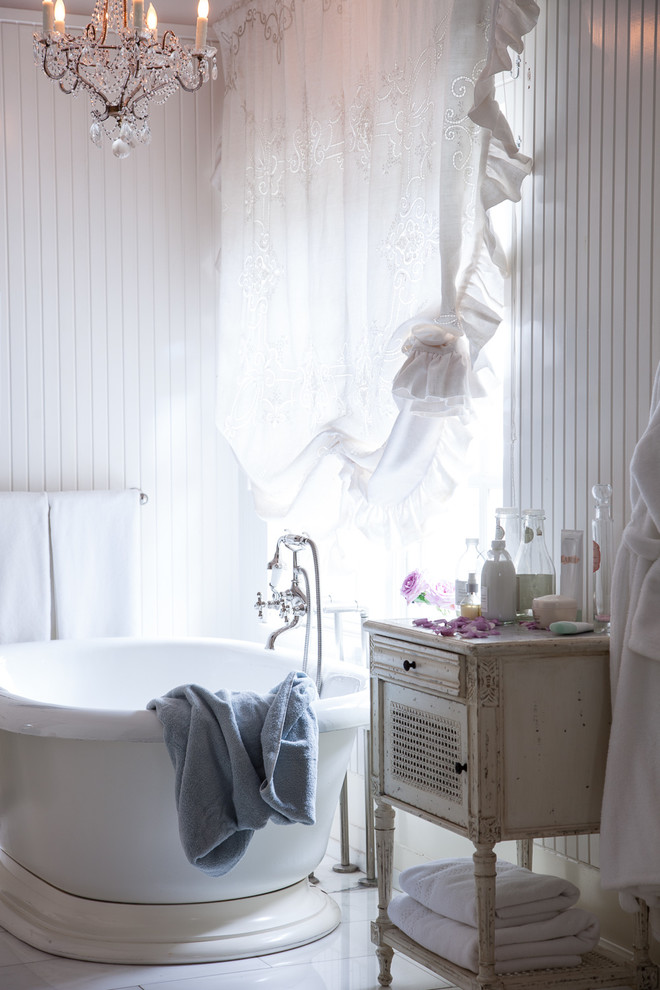 Exemple d'une salle de bain principale romantique avec une baignoire indépendante, un mur blanc et un sol en marbre.