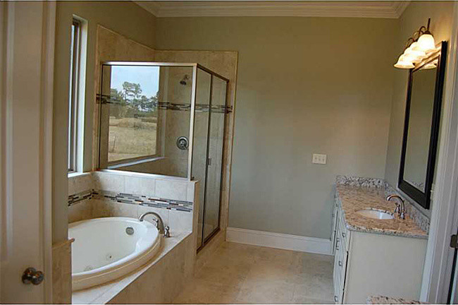 Modern inredning av ett stort en-suite badrum, med ett undermonterad handfat, luckor med upphöjd panel, vita skåp, granitbänkskiva, ett platsbyggt badkar, en dubbeldusch, en toalettstol med hel cisternkåpa, keramikplattor, beige väggar och klinkergolv i keramik