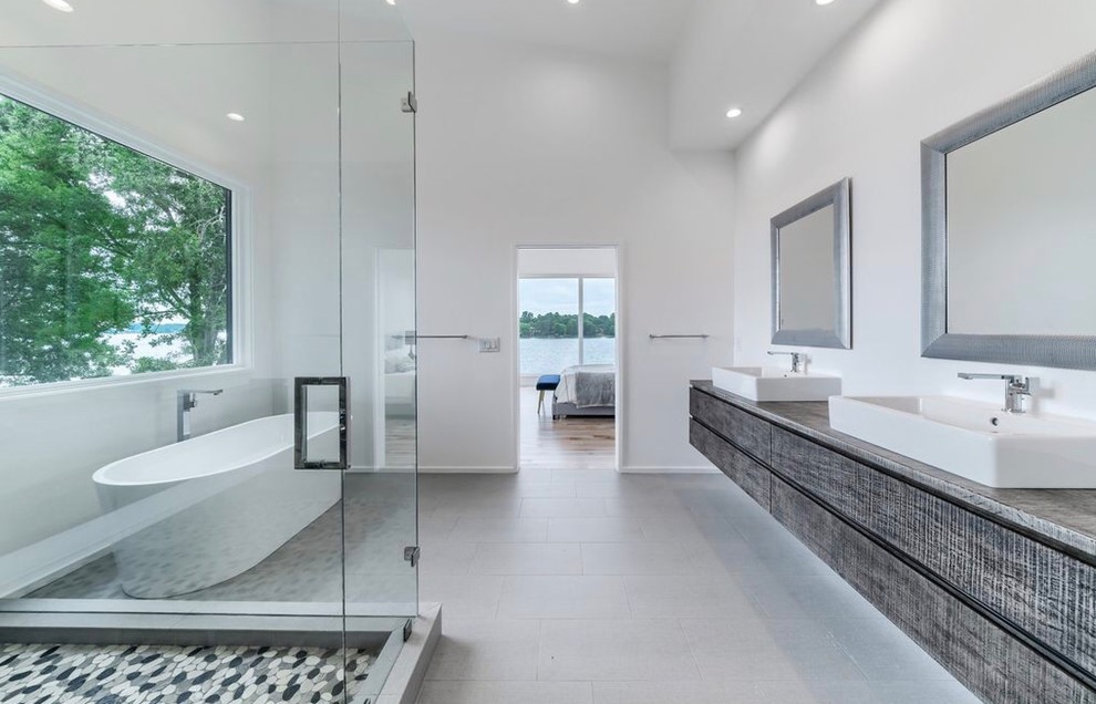 Пример оригинального дизайна: большая главная ванная комната в стиле модернизм с плоскими фасадами, серыми фасадами, отдельно стоящей ванной, угловым душем, унитазом-моноблоком, черно-белой плиткой, керамической плиткой, белыми стенами, полом из керамической плитки, накладной раковиной, столешницей из бетона, серым полом, душем с распашными дверями и разноцветной столешницей