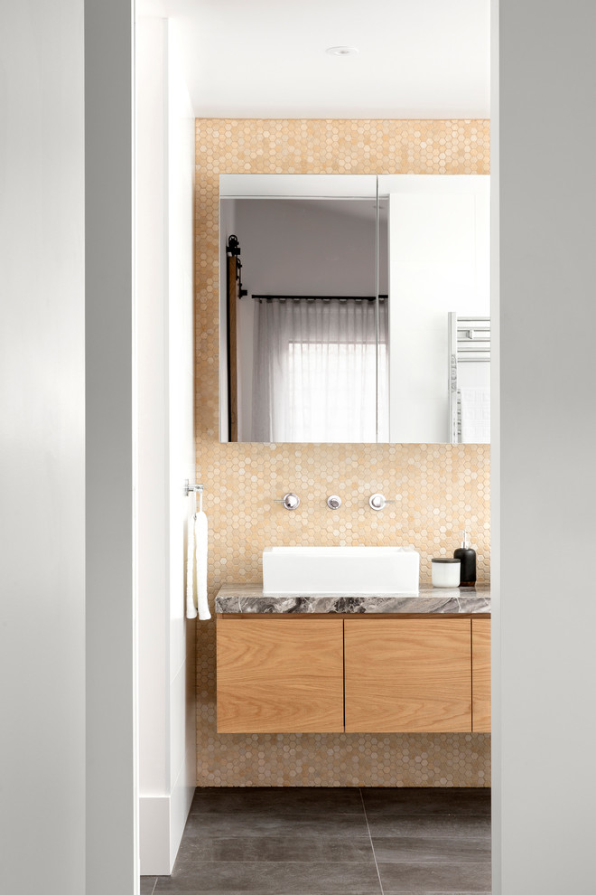 Modern inredning av ett mellanstort en-suite badrum, med släta luckor, skåp i mellenmörkt trä, ett fristående badkar, en öppen dusch, en vägghängd toalettstol, vit kakel, keramikplattor, vita väggar, klinkergolv i porslin, ett fristående handfat, marmorbänkskiva, grått golv och med dusch som är öppen