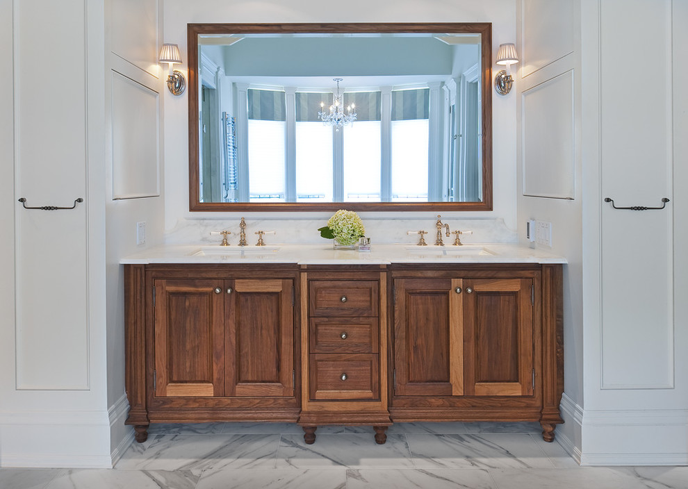 Klassisk inredning av ett stort en-suite badrum, med luckor med infälld panel, skåp i mellenmörkt trä, ett fristående badkar, en hörndusch, vita väggar, marmorgolv, ett undermonterad handfat och marmorbänkskiva