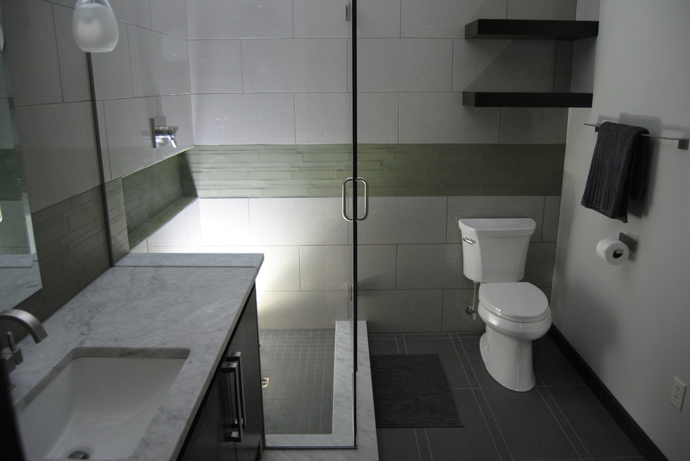 Cette photo montre une salle de bain principale moderne en bois foncé de taille moyenne avec un lavabo encastré, un placard à porte plane, un plan de toilette en marbre, une douche d'angle, WC séparés, un carrelage gris, un carrelage en pâte de verre, un mur gris et un sol en carrelage de porcelaine.